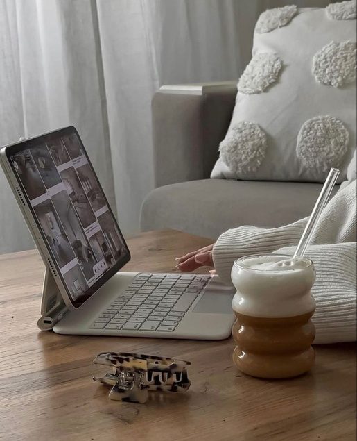Tablet with a keyboard on a wooden coffee table beside an iced coffee